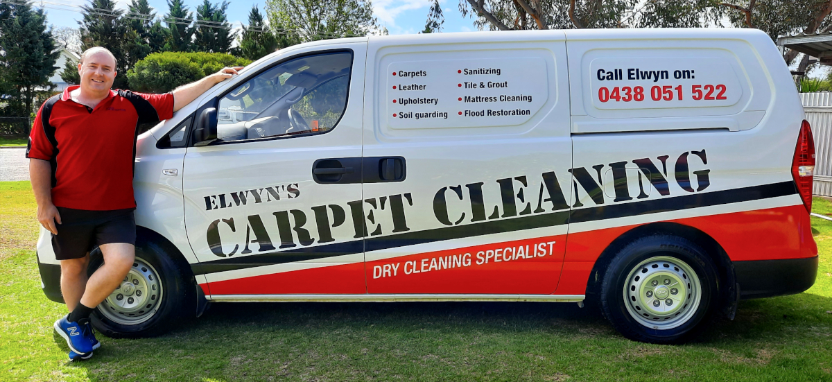 Elwyn standing next to his van showing signage